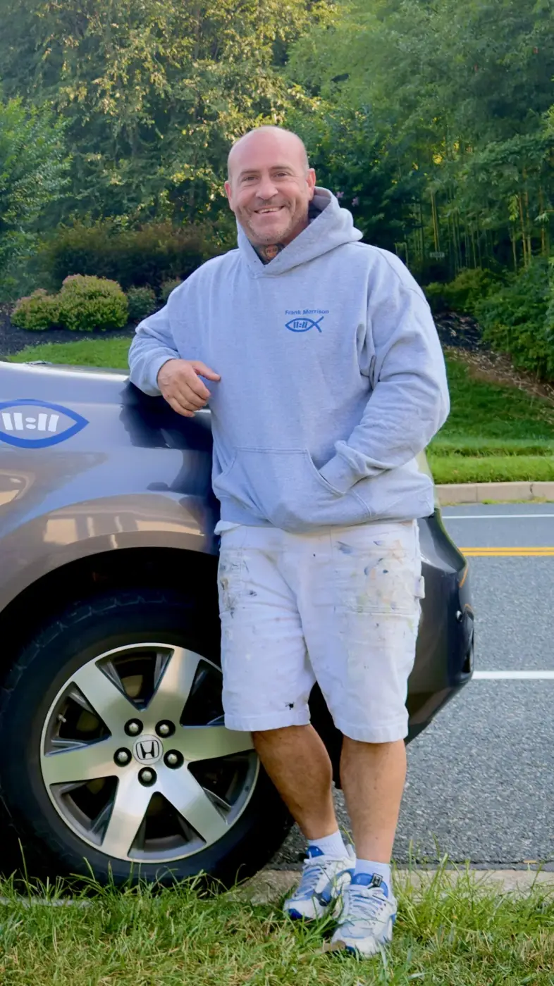 Frank Morrison leaning against a Prodigal Son Painting vehicle